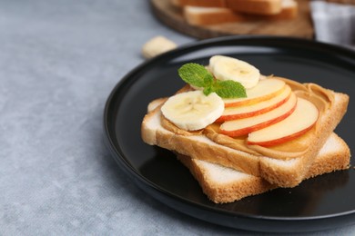 Photo of Tasty sandwich with peanut butter, apple, banana and mint on grey table, closeup