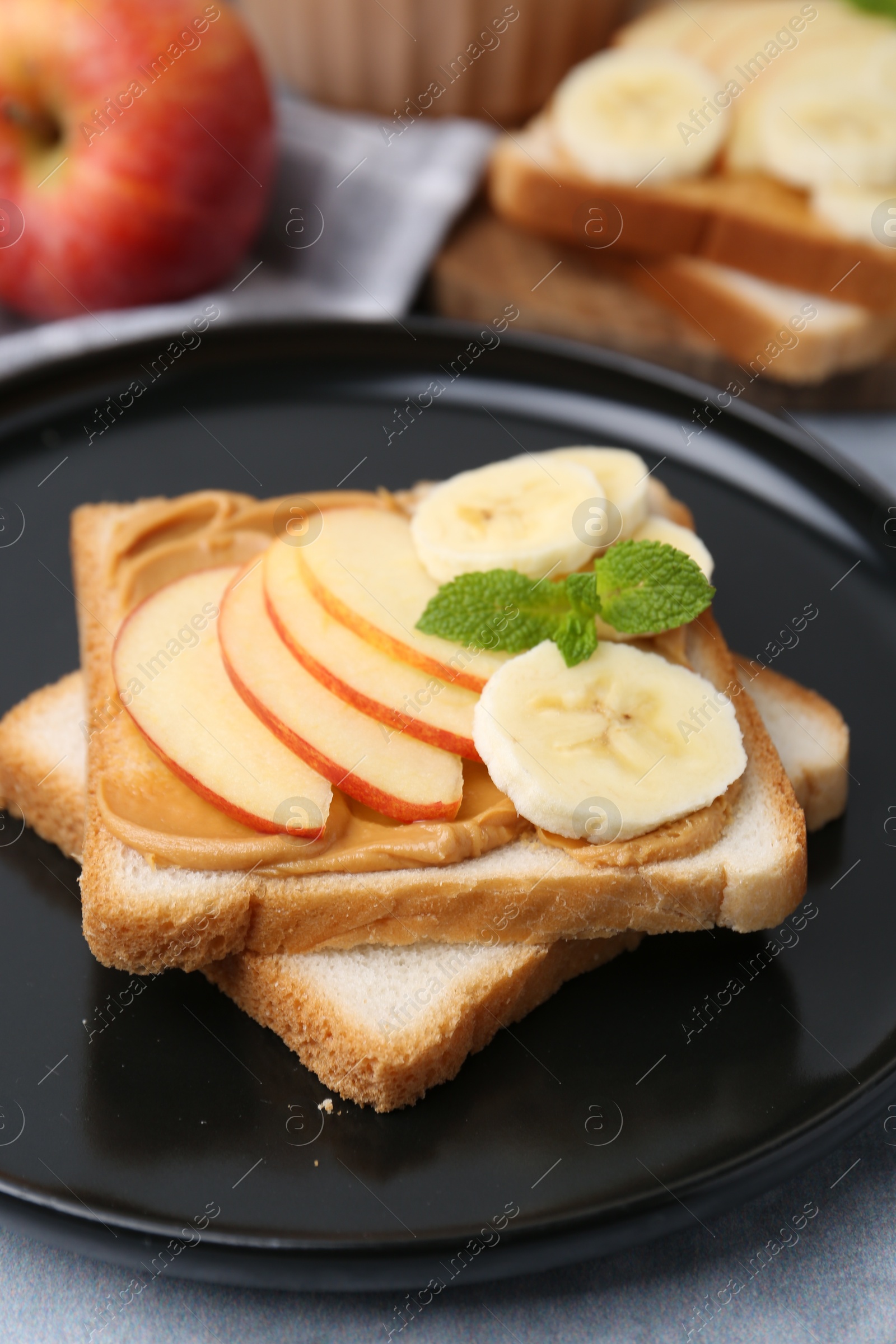 Photo of Tasty sandwich with peanut butter, apple, banana and mint on table, closeup