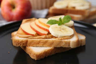 Photo of Tasty sandwich with peanut butter, apple, banana and mint on plate, closeup