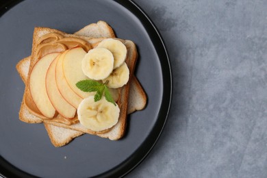 Photo of Tasty sandwich with peanut butter, apple, banana and mint on grey table, top view. Space for text