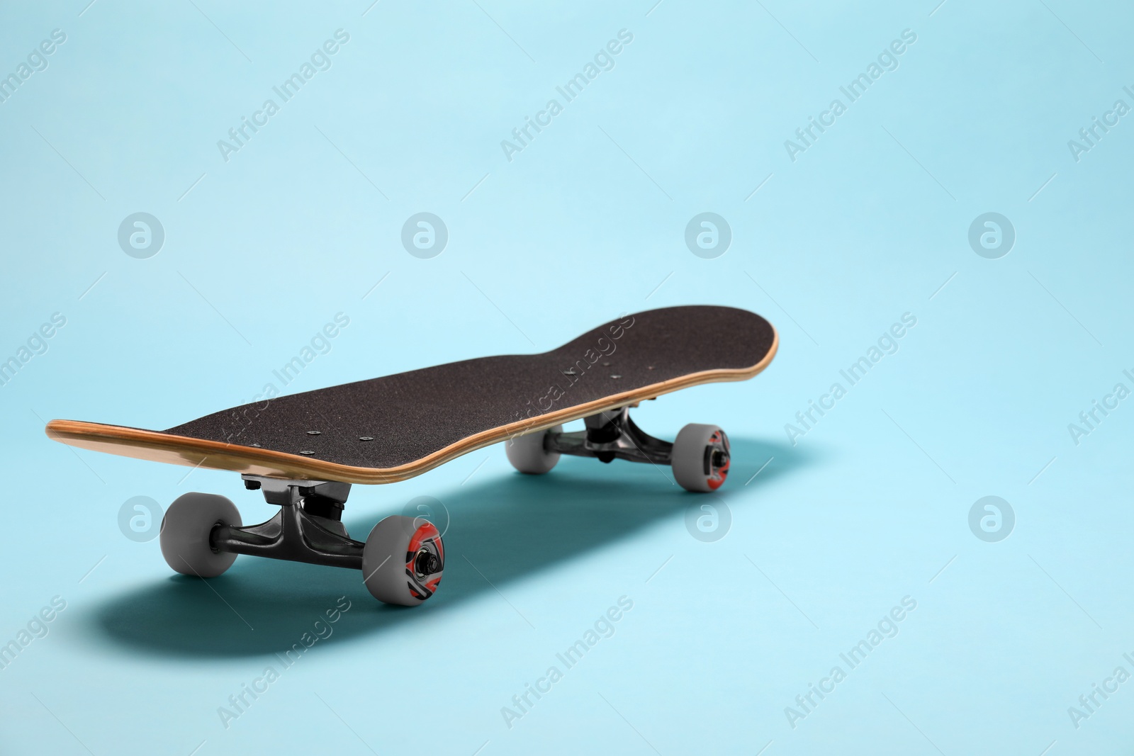 Photo of One skateboard on light blue background, space for text. Sports equipment