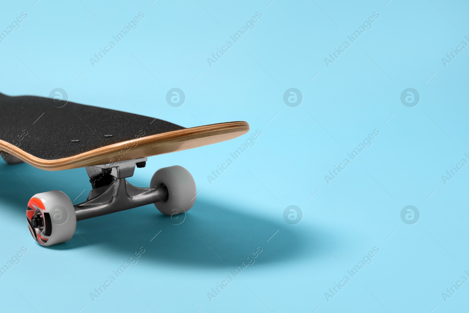 Photo of One skateboard on light blue background, closeup. Space for text