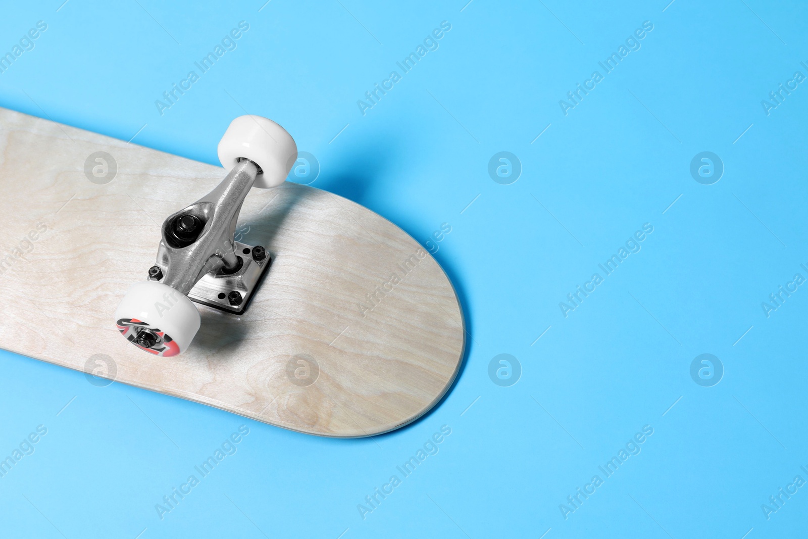 Photo of One skateboard on light blue background, closeup. Space for text