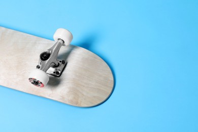 Photo of One skateboard on light blue background, closeup. Space for text