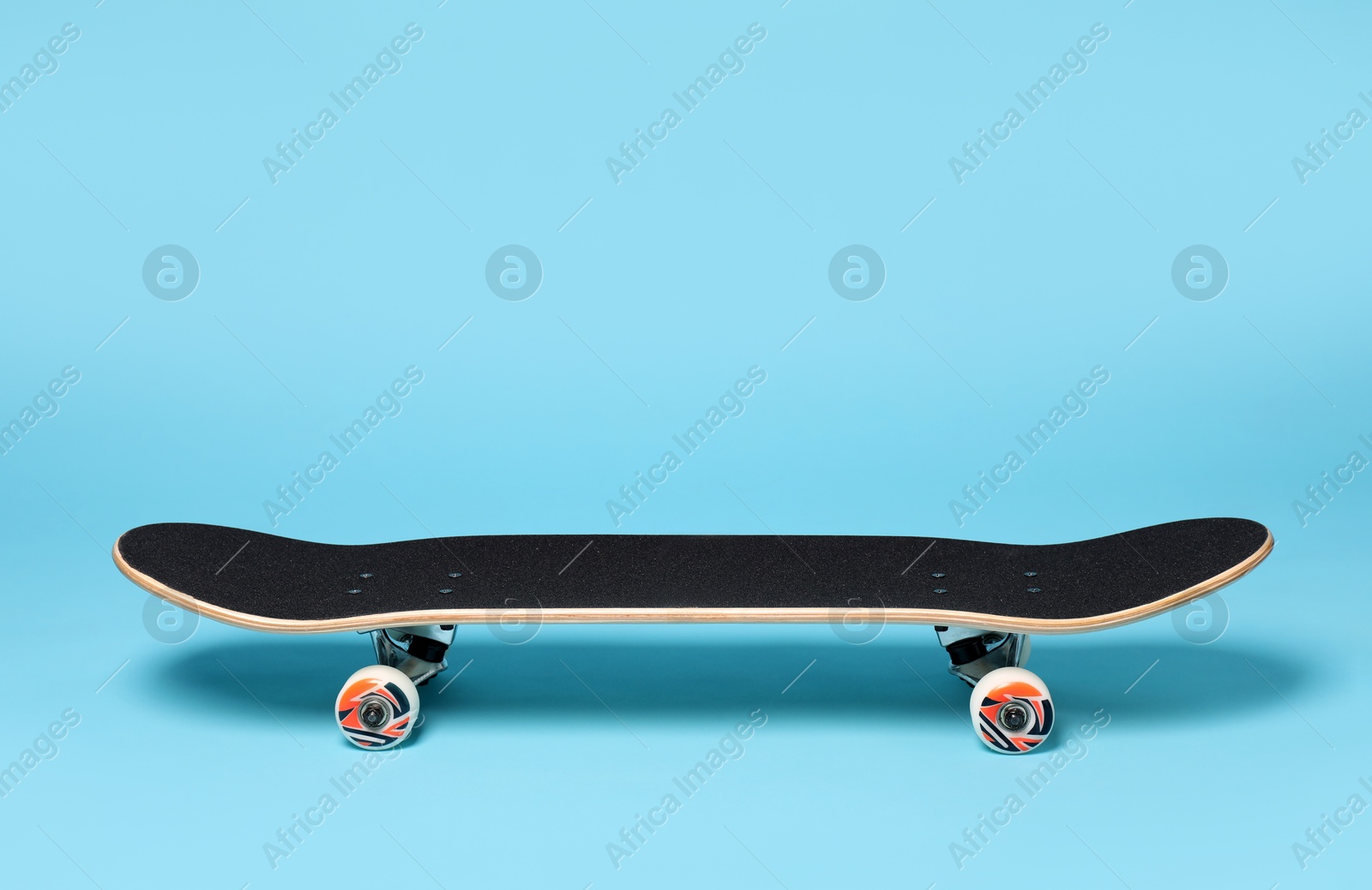 Photo of One skateboard on light blue background. Sports equipment