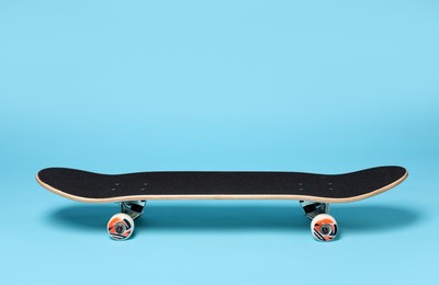 Photo of One skateboard on light blue background. Sports equipment