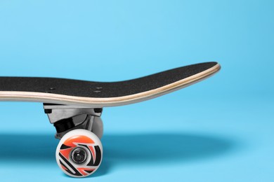 Photo of One skateboard on light blue background, closeup. Sports equipment