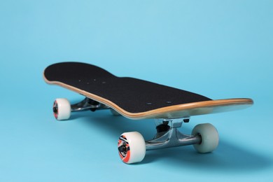 Photo of One skateboard on light blue background, closeup. Sports equipment