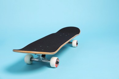 Photo of One skateboard on light blue background, closeup. Space for text