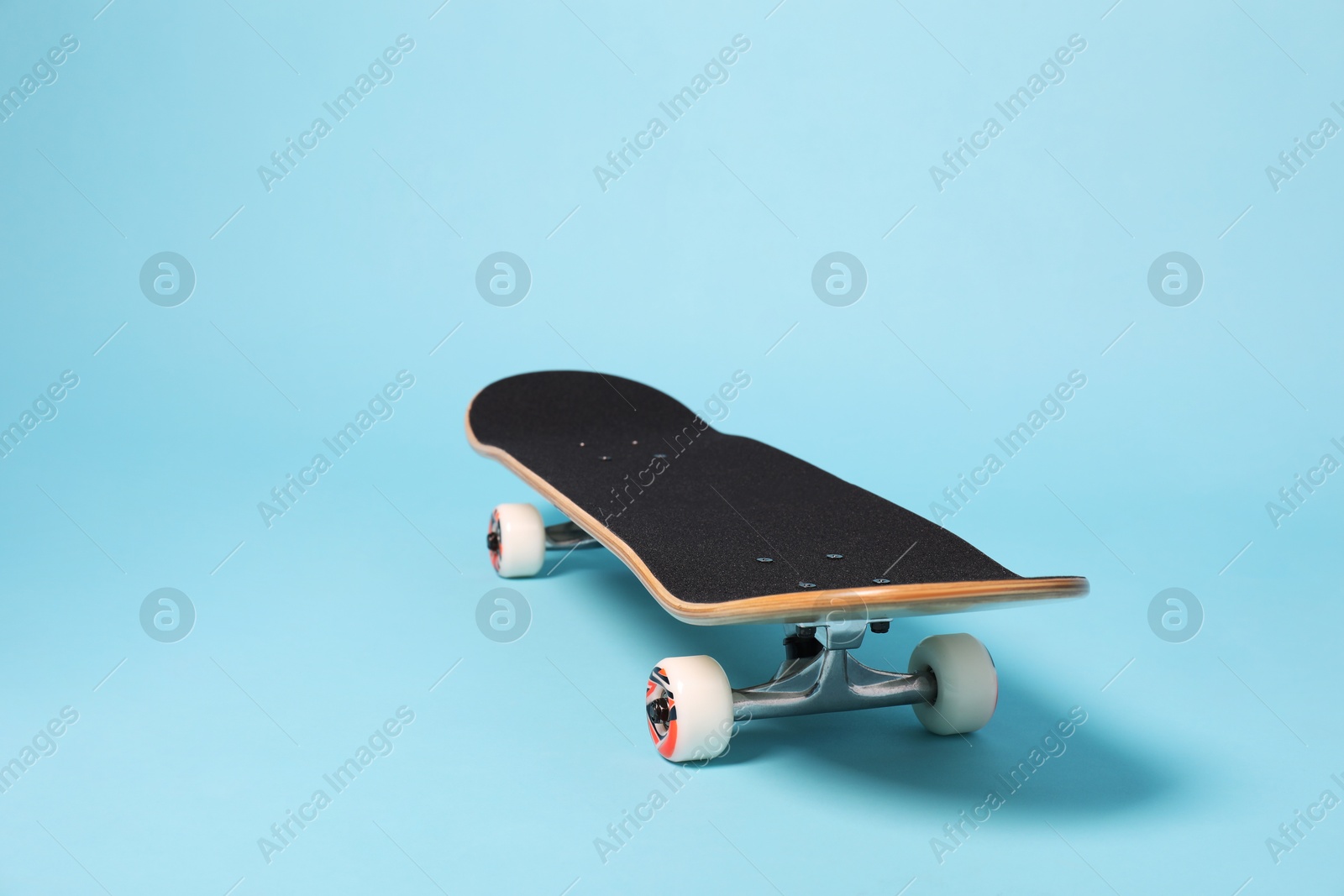 Photo of One skateboard on light blue background, space for text. Sports equipment