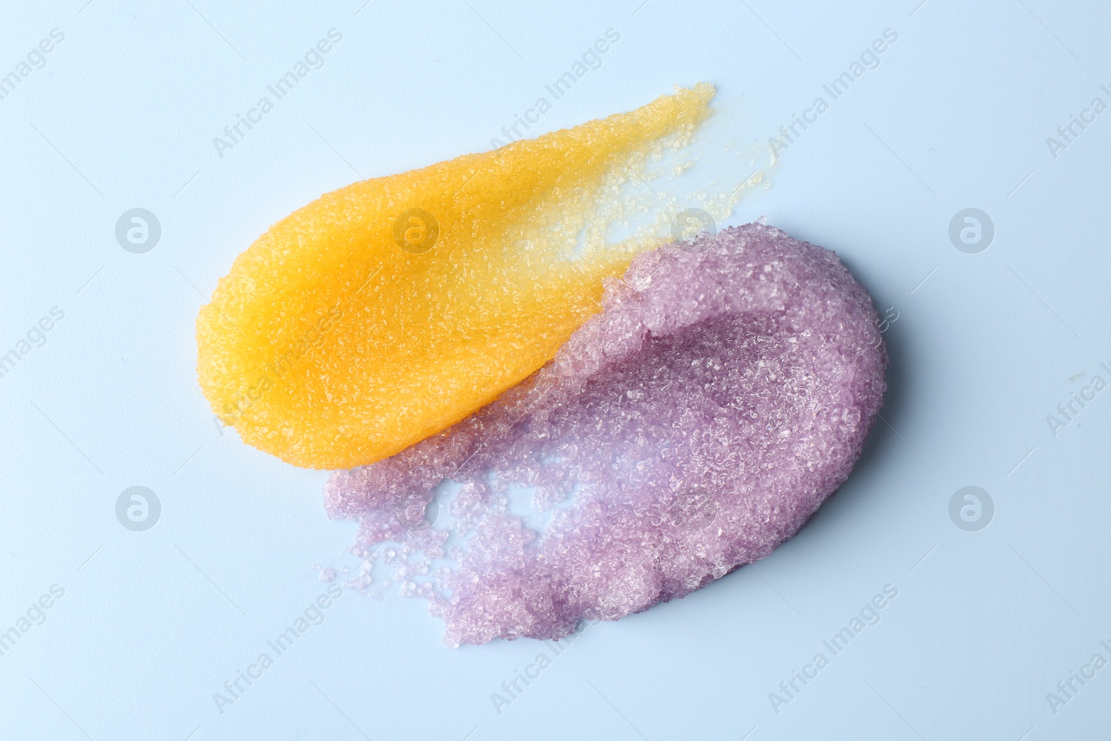 Photo of Smears of body scrubs on light background, top view