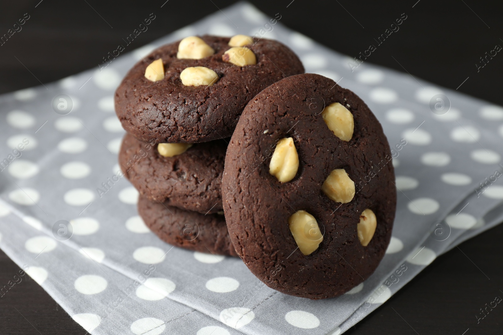 Photo of Delicious chocolate cookies with hazelnuts on black table, closeup