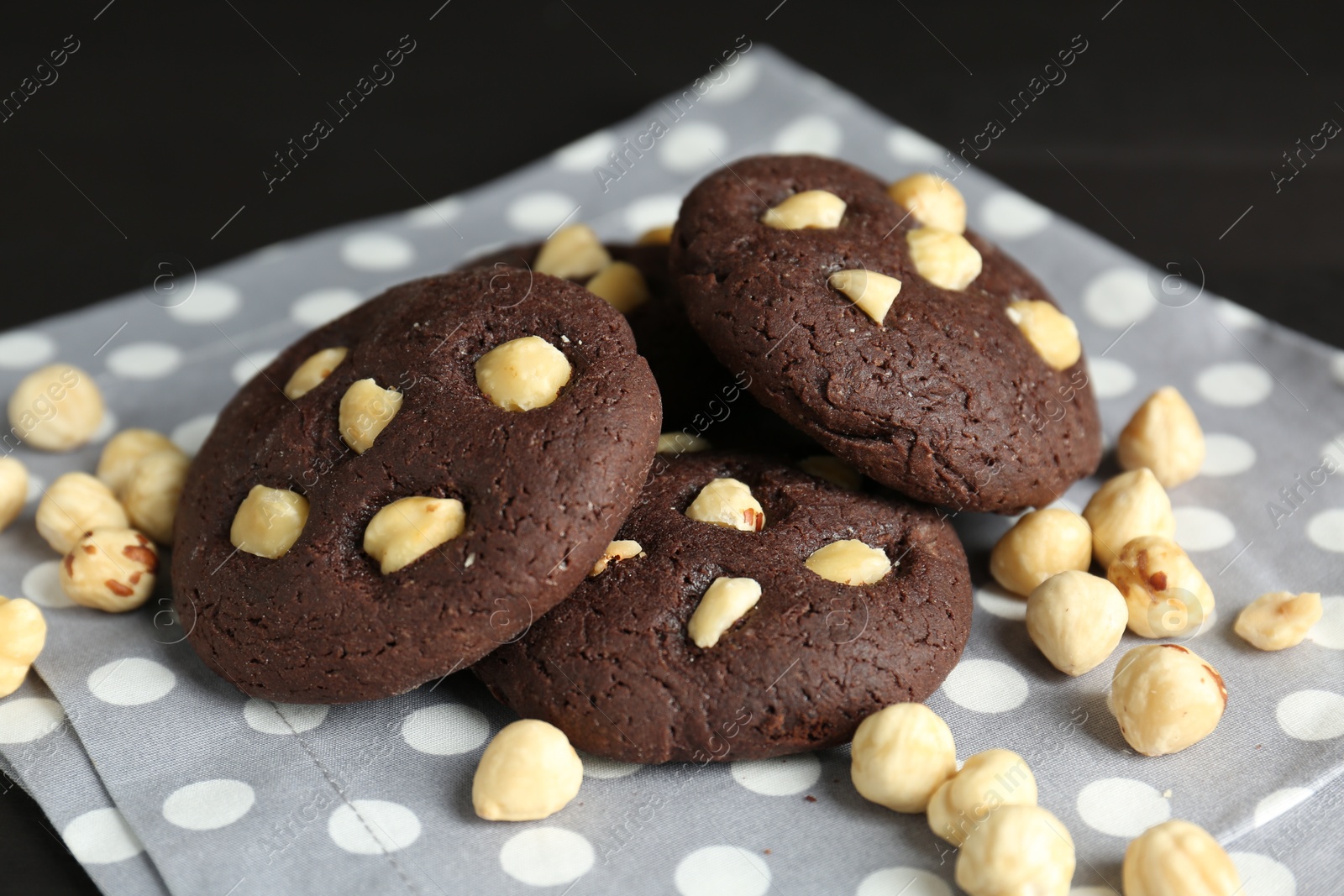 Photo of Delicious chocolate cookies with hazelnuts on black table, closeup