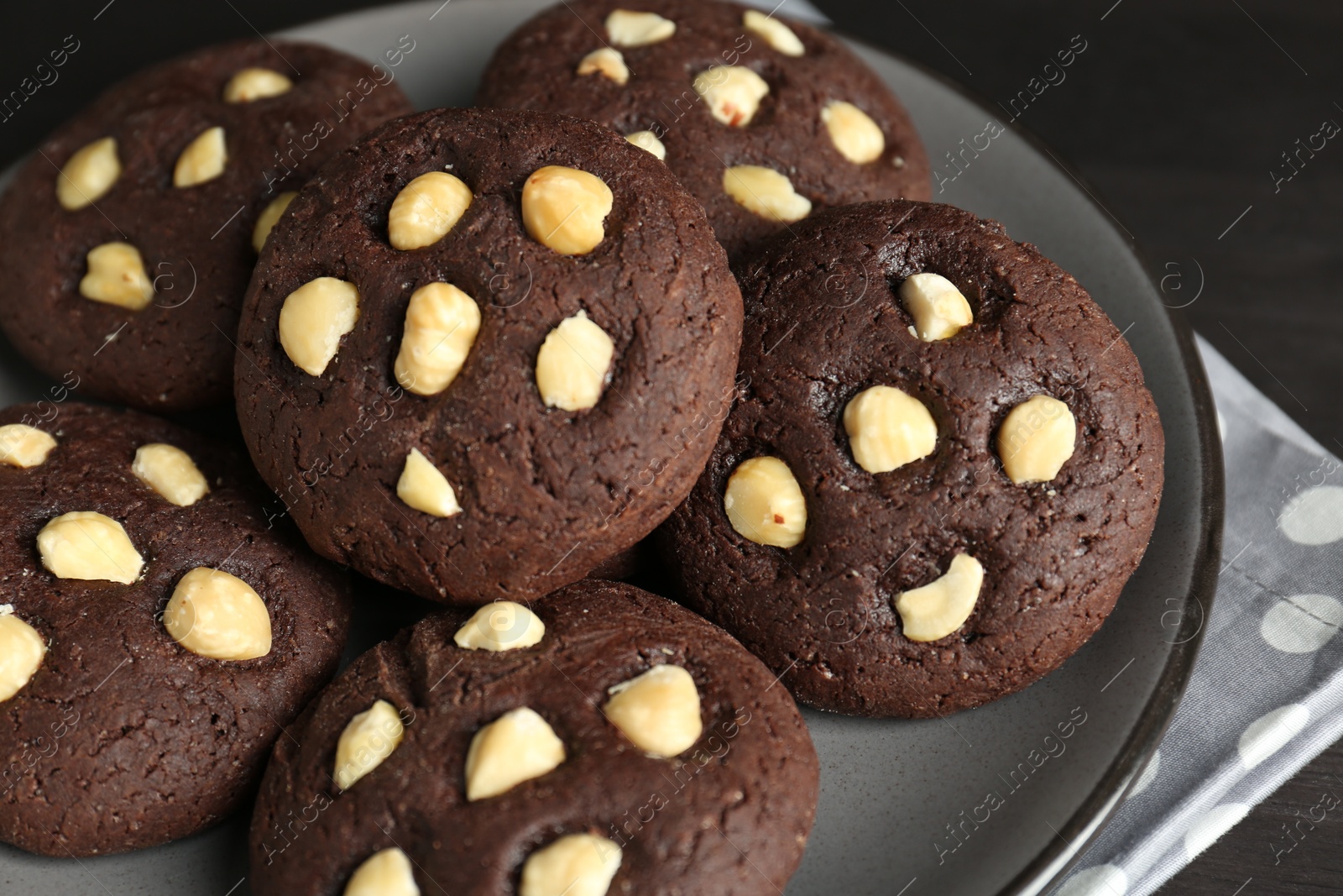 Photo of Delicious chocolate cookies with hazelnuts on black table, closeup