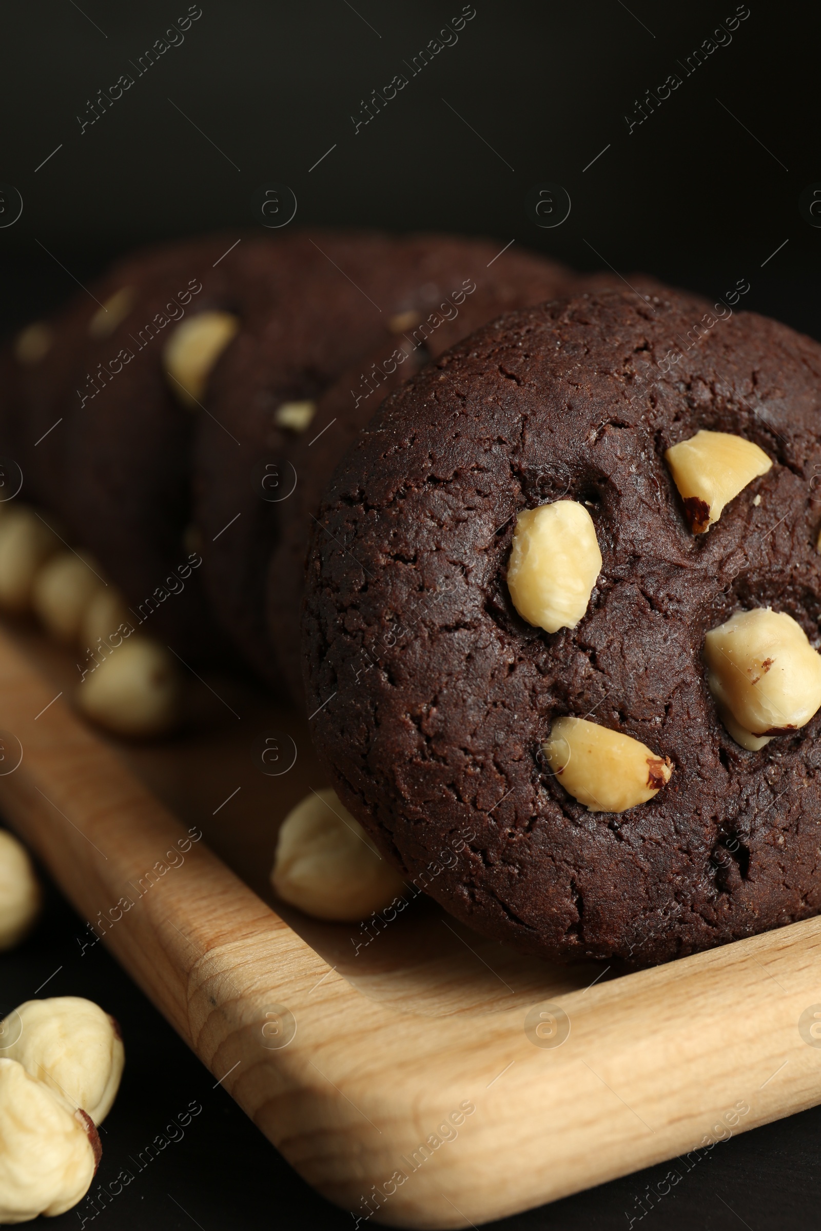 Photo of Delicious chocolate cookies with hazelnuts on black table, closeup