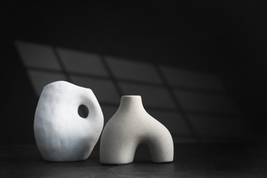 Photo of Stylish ceramic vases on black background. Space for text