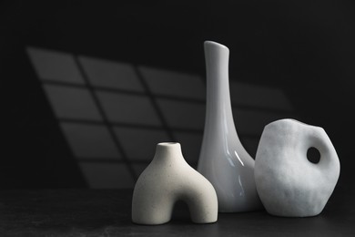 Stylish ceramic vases on black background. Space for text