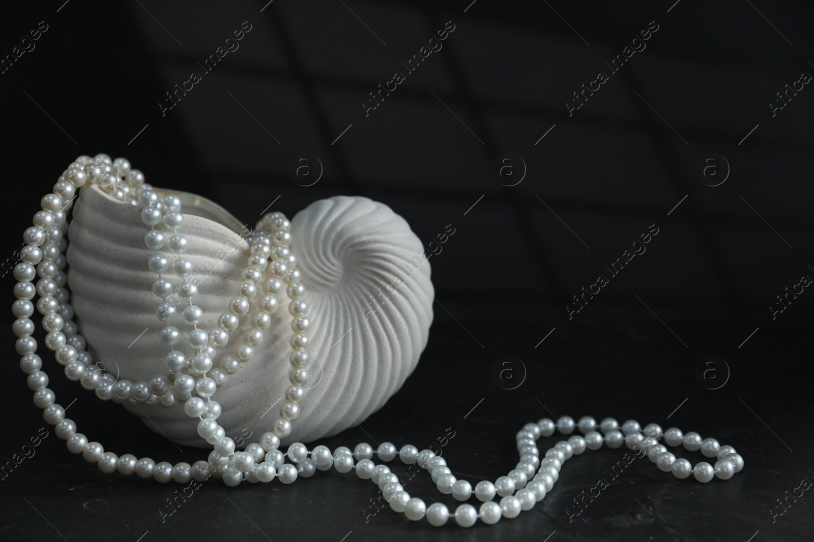 Photo of Stylish vase and elegant pearl jewelry on black background, space for text