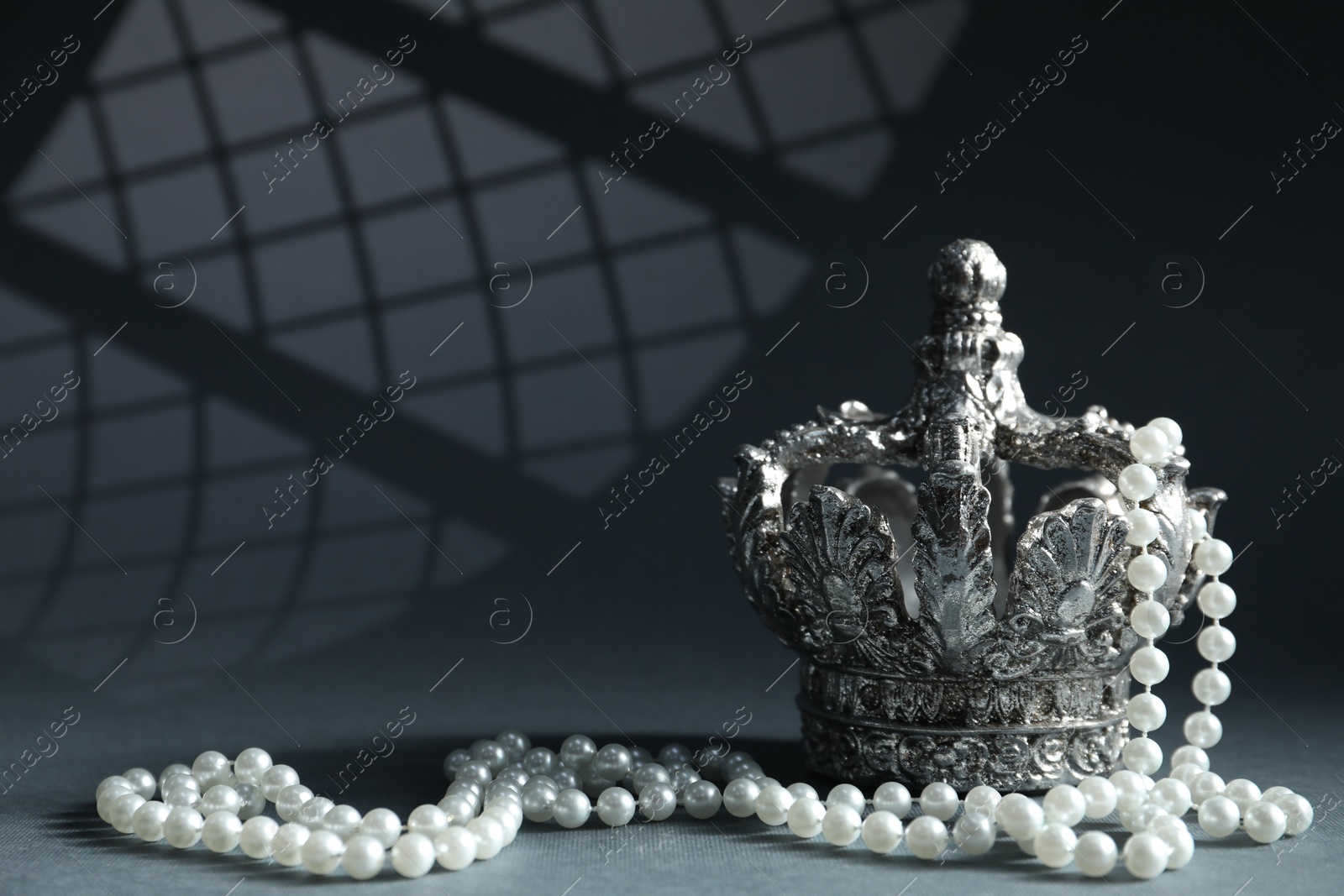 Photo of Stylish silver crown and elegant pearl jewelry against grey background