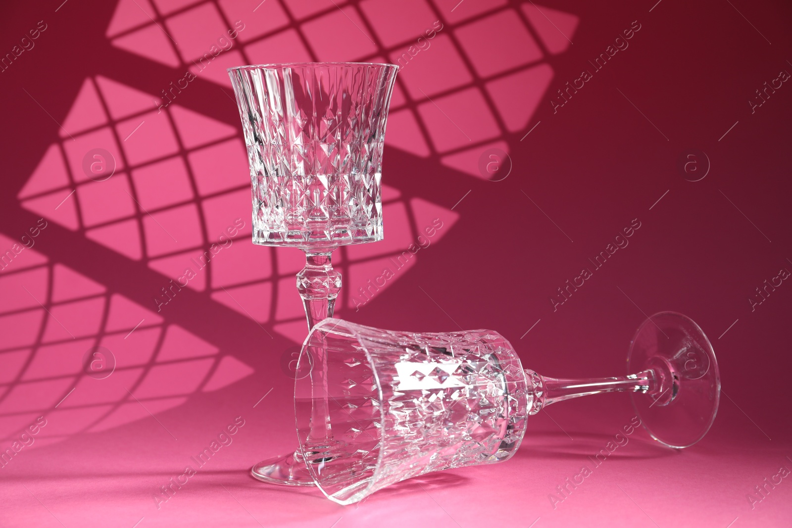 Photo of Two elegant wine glasses on pink background