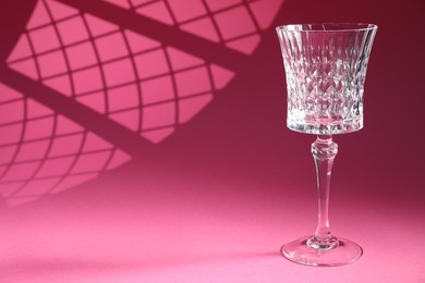 Photo of Elegant wine glass on pink background, space for text