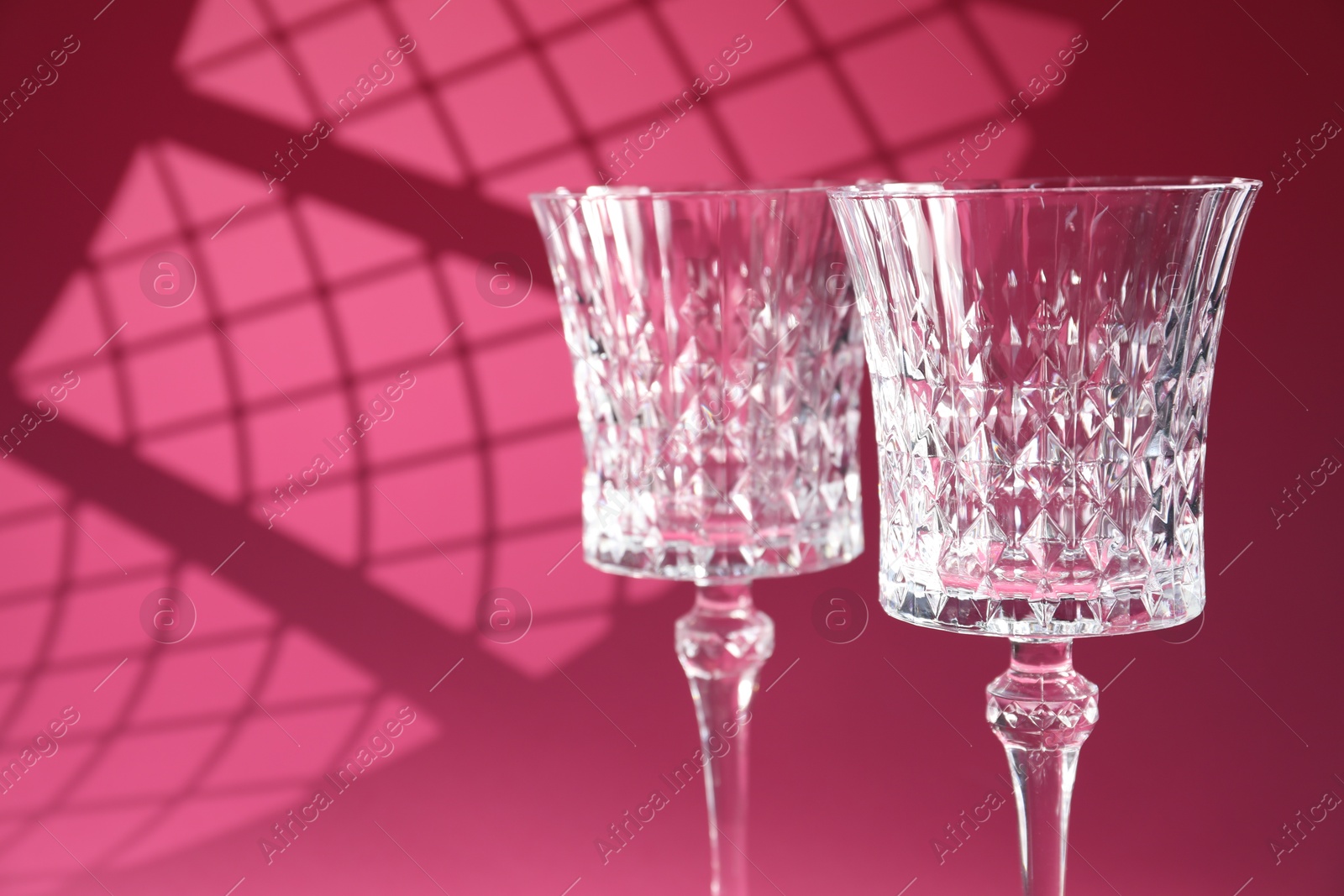 Photo of Elegant wine glasses on pink background, space for text