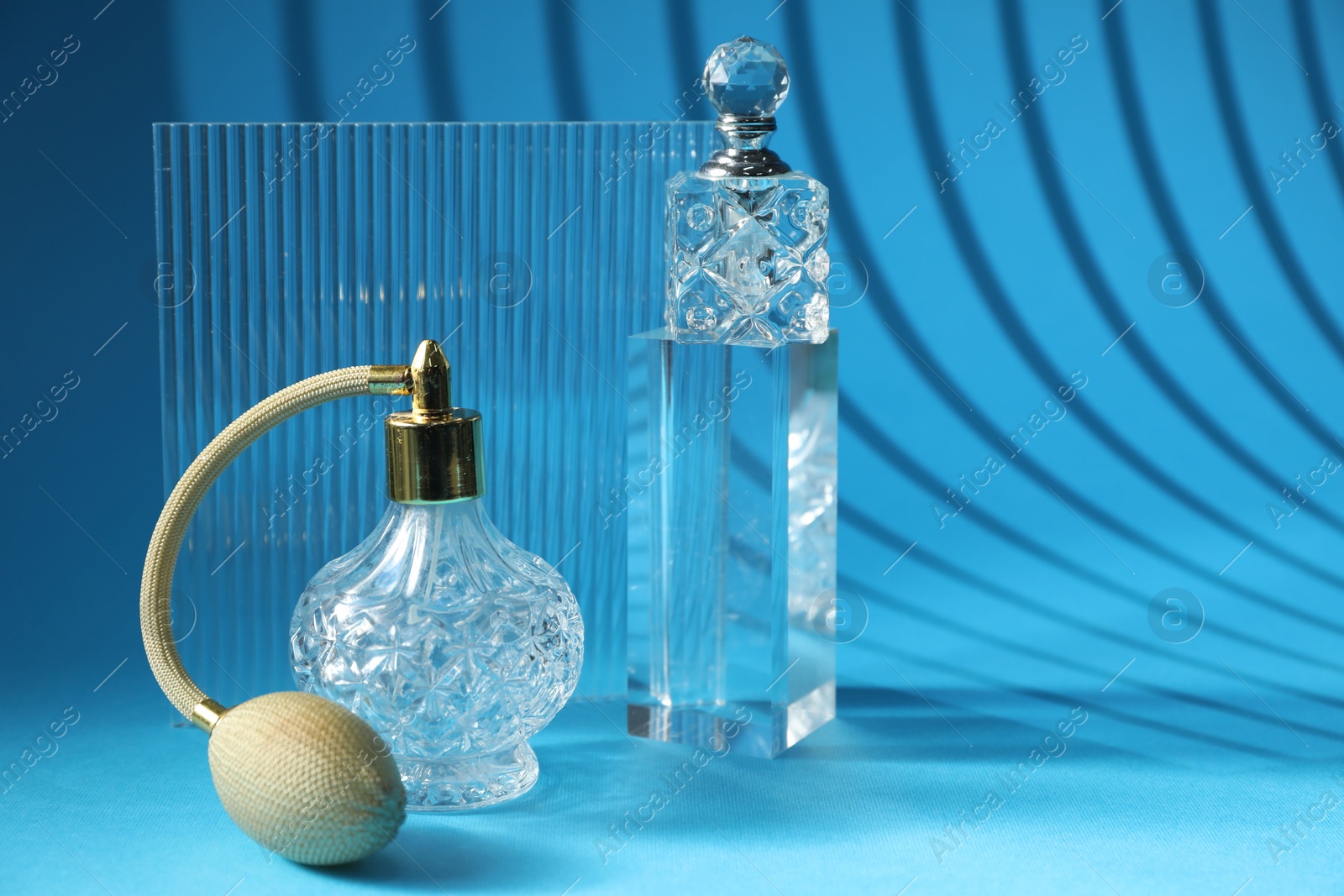 Photo of Stylish presentation of perfume bottles on light blue background, space for text