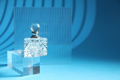 Photo of Stylish presentation of perfume bottle on light blue background, space for text