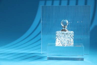 Photo of Stylish presentation of perfume bottle on light blue background, space for text