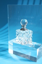 Photo of Stylish presentation of perfume bottle on light blue background