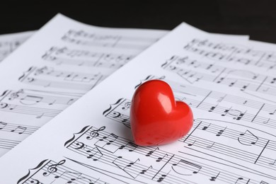 Photo of Heart figure and musical notes on black background, closeup