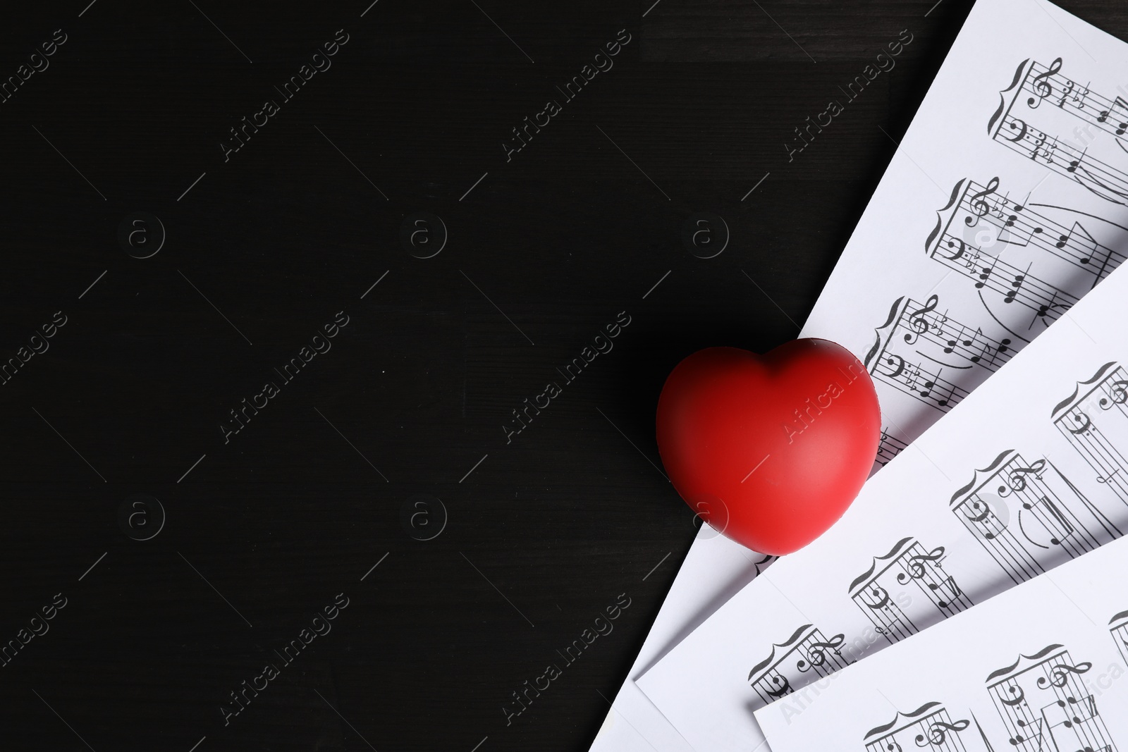 Photo of Heart figure and musical notes on black wooden background, top view. Space for text