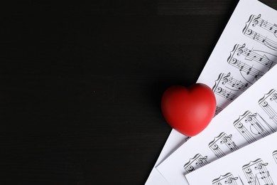 Photo of Heart figure and musical notes on black wooden background, top view. Space for text