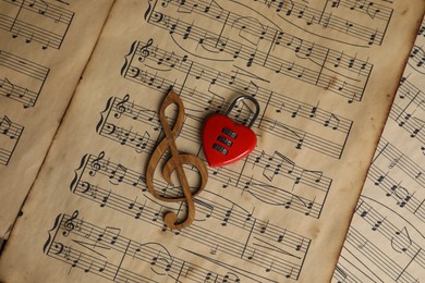 Photo of Clef figure and heart shaped padlock on musical notes, top view