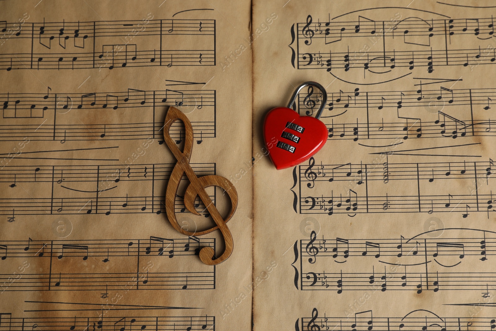 Photo of Clef figure and heart shaped padlock on musical notes, top view