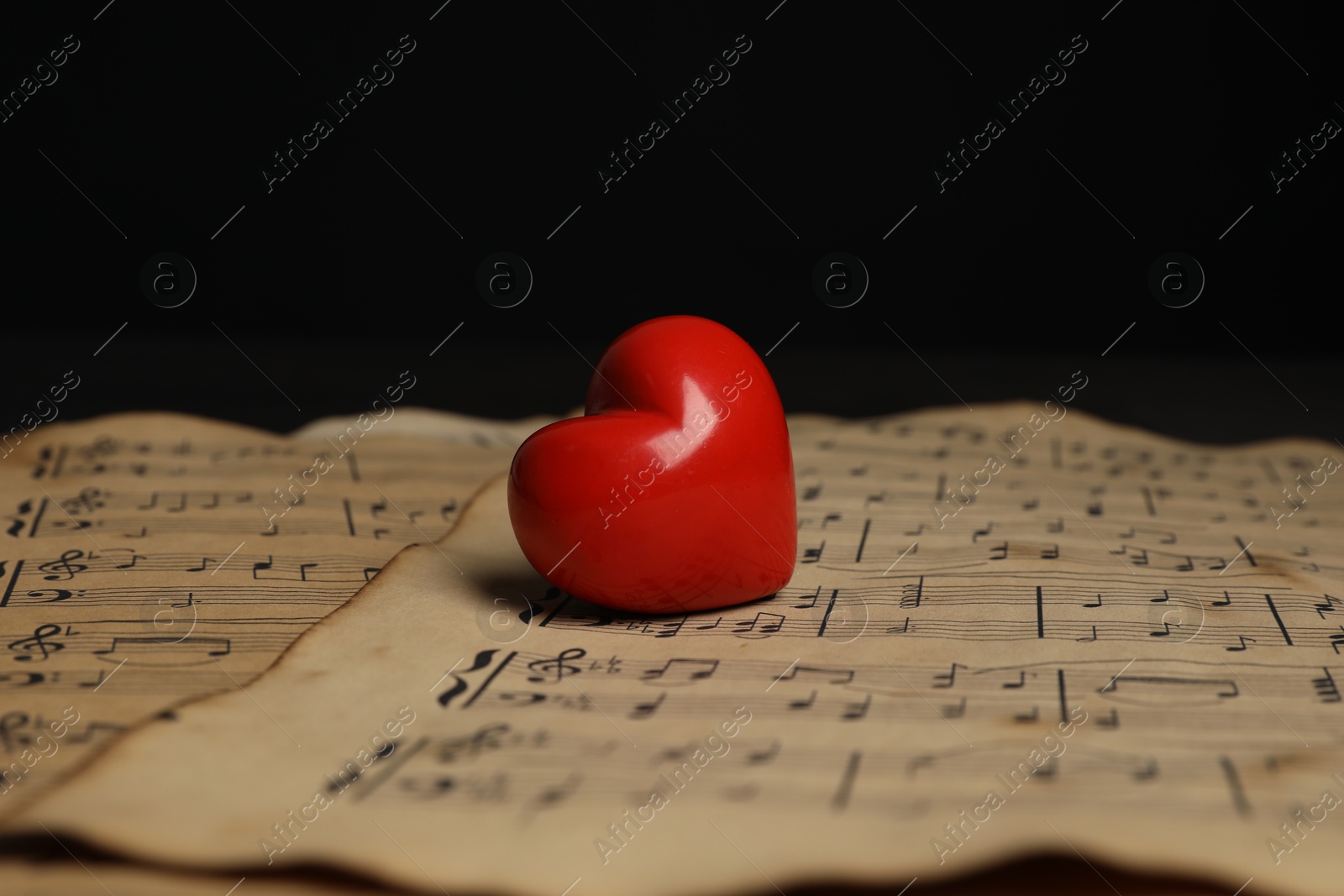 Photo of Heart figure and musical notes on black background, closeup