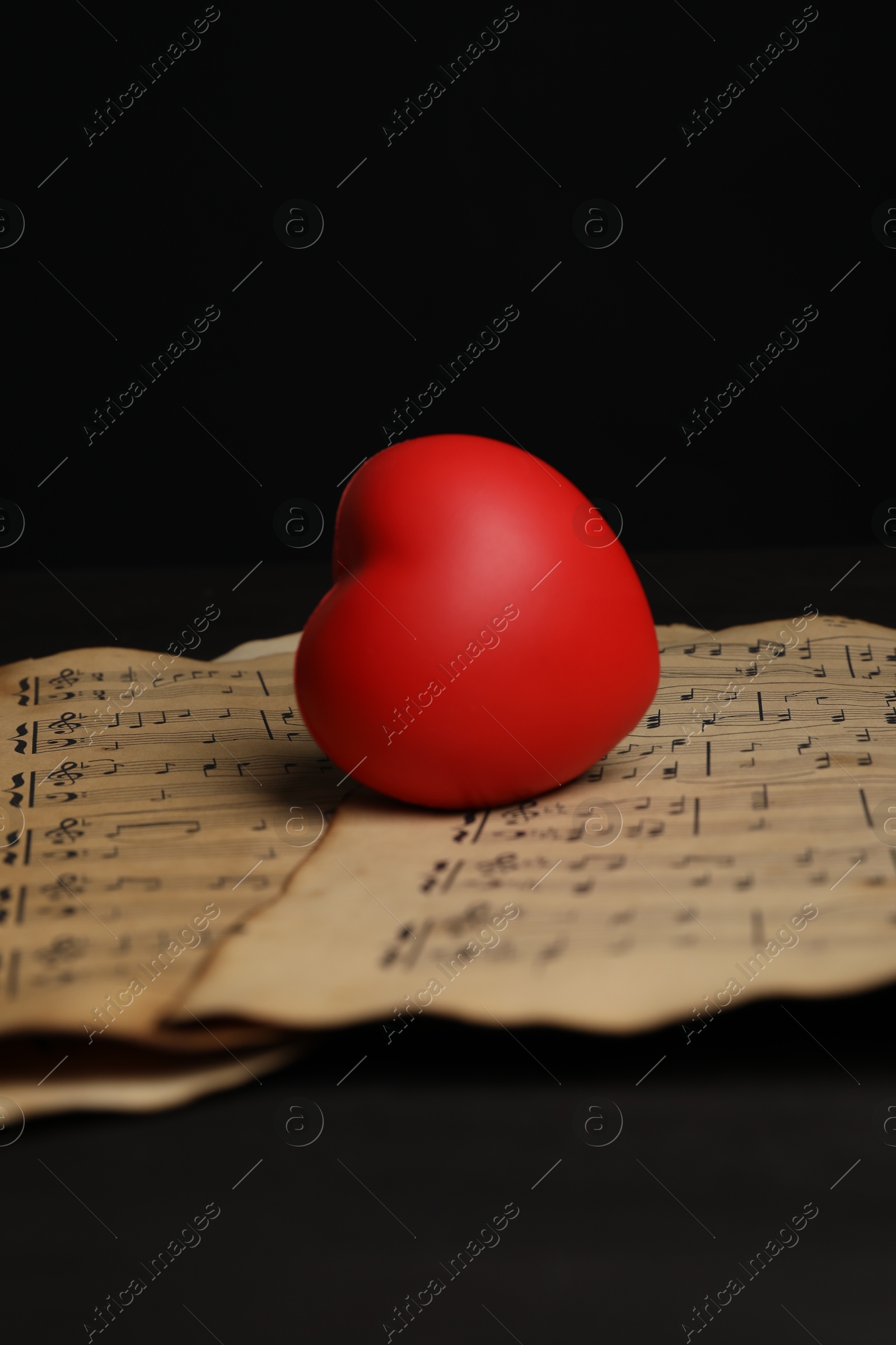 Photo of Heart figure and musical notes on black background, closeup