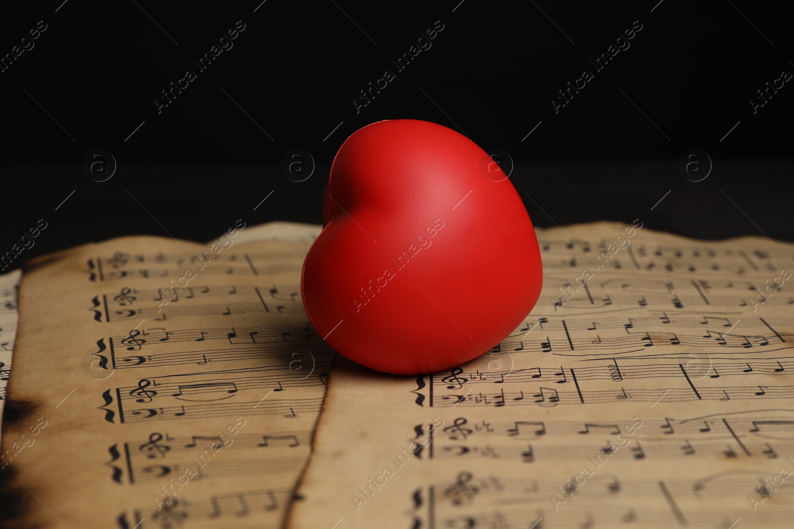 Photo of Heart figure and musical notes on black background, closeup