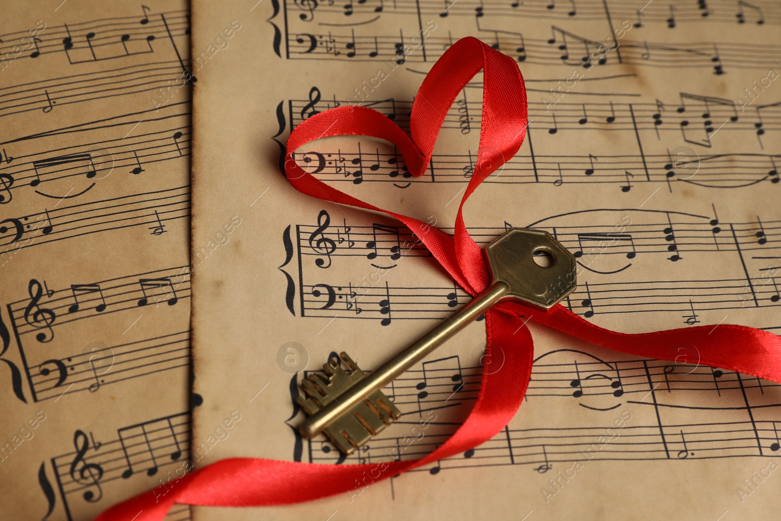 Photo of Key and heart shaped ribbon on musical notes, closeup