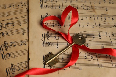 Key and heart shaped ribbon on musical notes, closeup