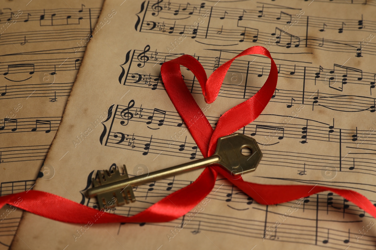 Photo of Key and heart shaped ribbon on musical notes, closeup