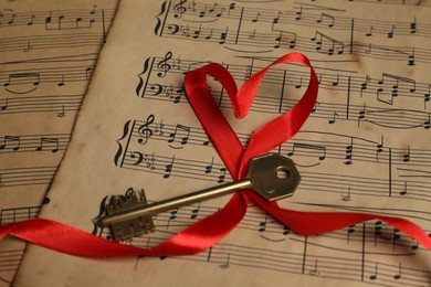 Key and heart shaped ribbon on musical notes, closeup