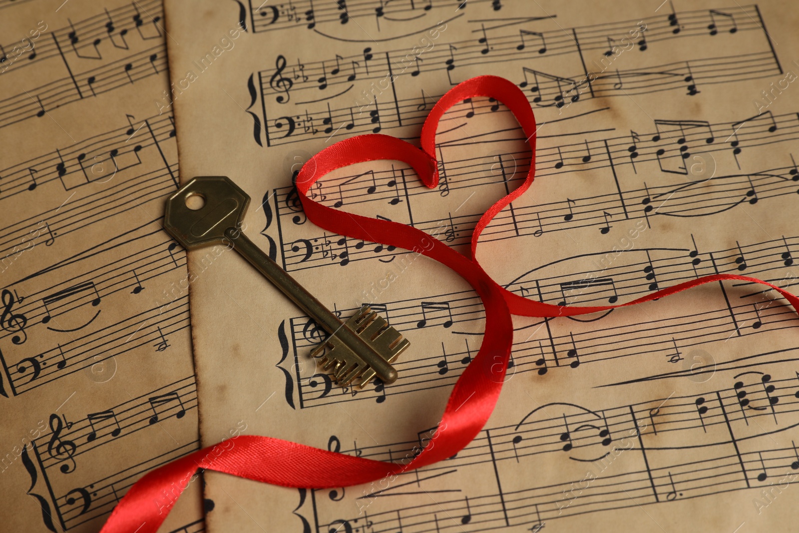 Photo of Key and heart shaped ribbon on musical notes, closeup