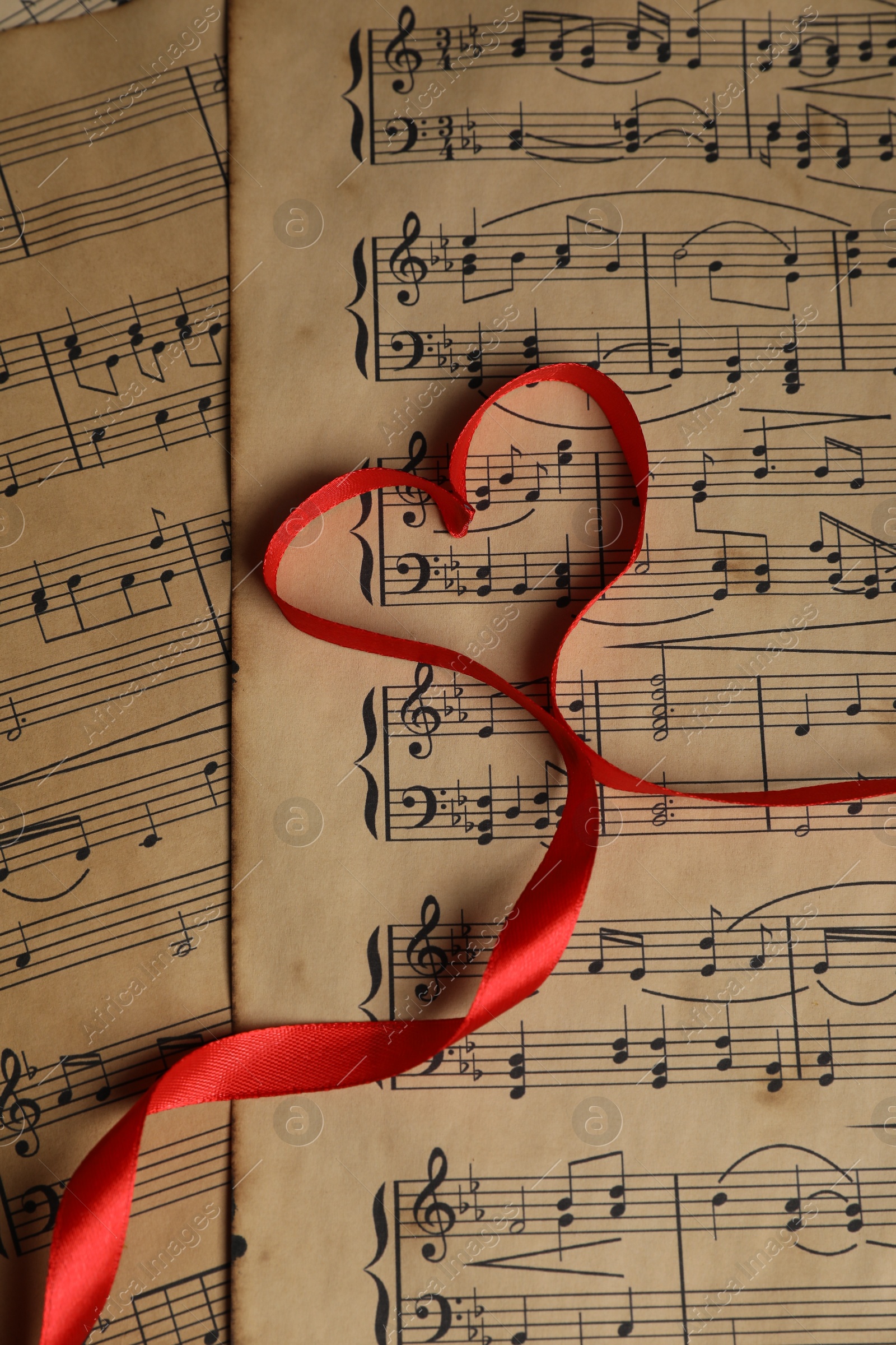 Photo of Heart shaped ribbon on musical notes, top view