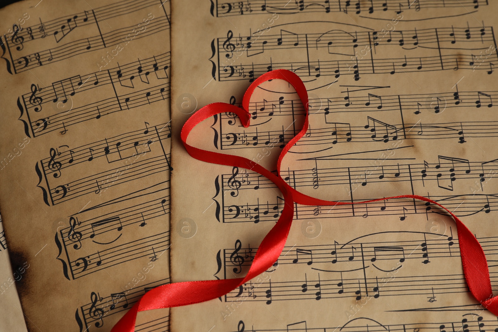 Photo of Heart shaped ribbon on musical notes, closeup