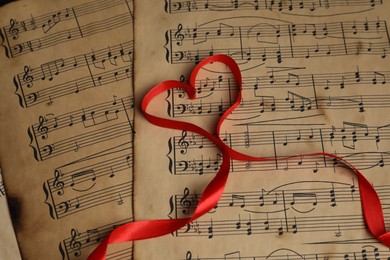 Heart shaped ribbon on musical notes, closeup