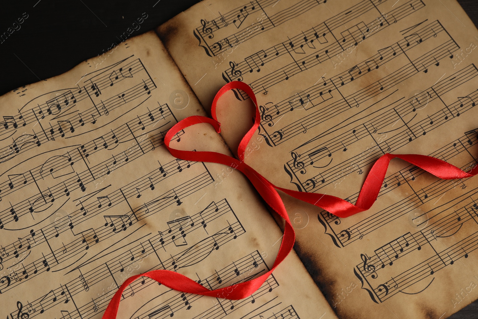 Photo of Heart shaped ribbon on musical notes, closeup