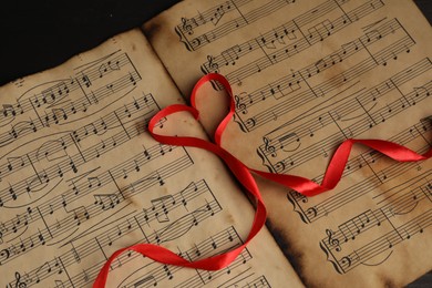 Photo of Heart shaped ribbon on musical notes, closeup