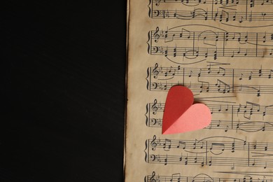 Photo of Paper heart and musical notes on black background, top view. Space for text