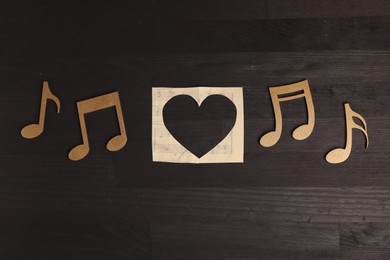 Paper heart and musical note figures on black wooden background, flat lay